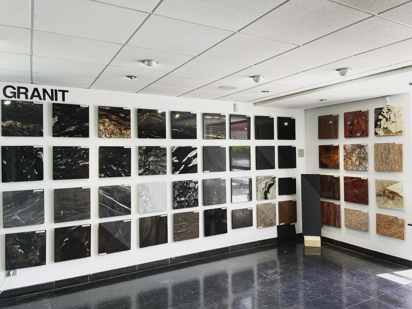 Mur d'exposition de carreaux de granit avec des rangées d'échantillons de pierre noire, grise et beige