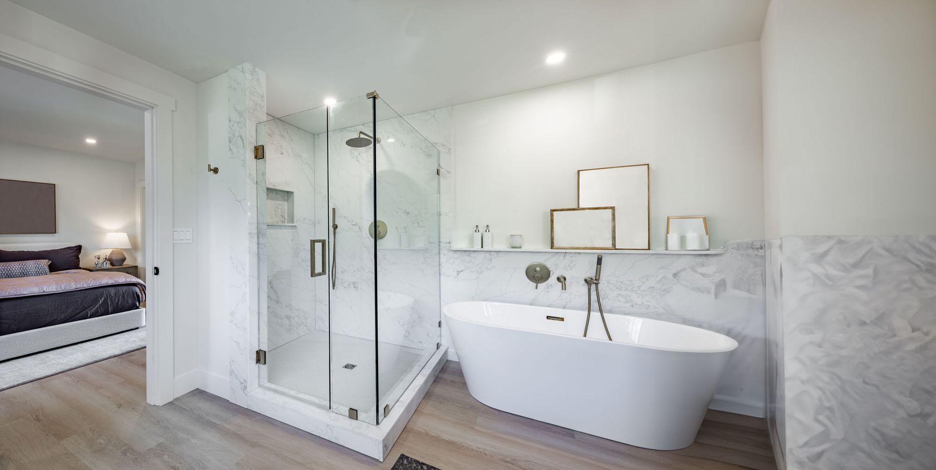 Salle de bains d'un blanc éclatant avec douche en verre, baignoire îlot et revêtements muraux en marbre.