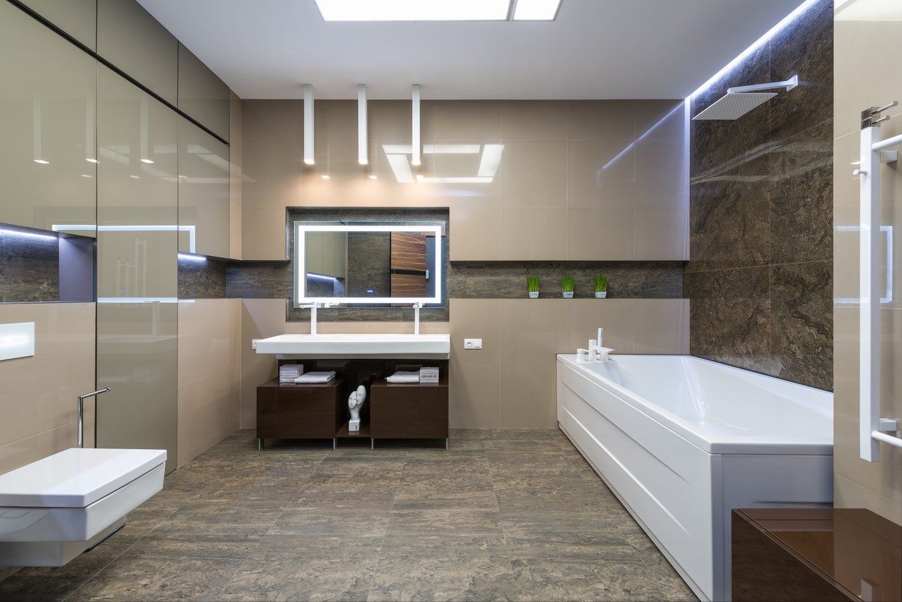 Salle de bains moderne avec douche en verre, double vasque, baignoire blanche et murs carrelés beiges