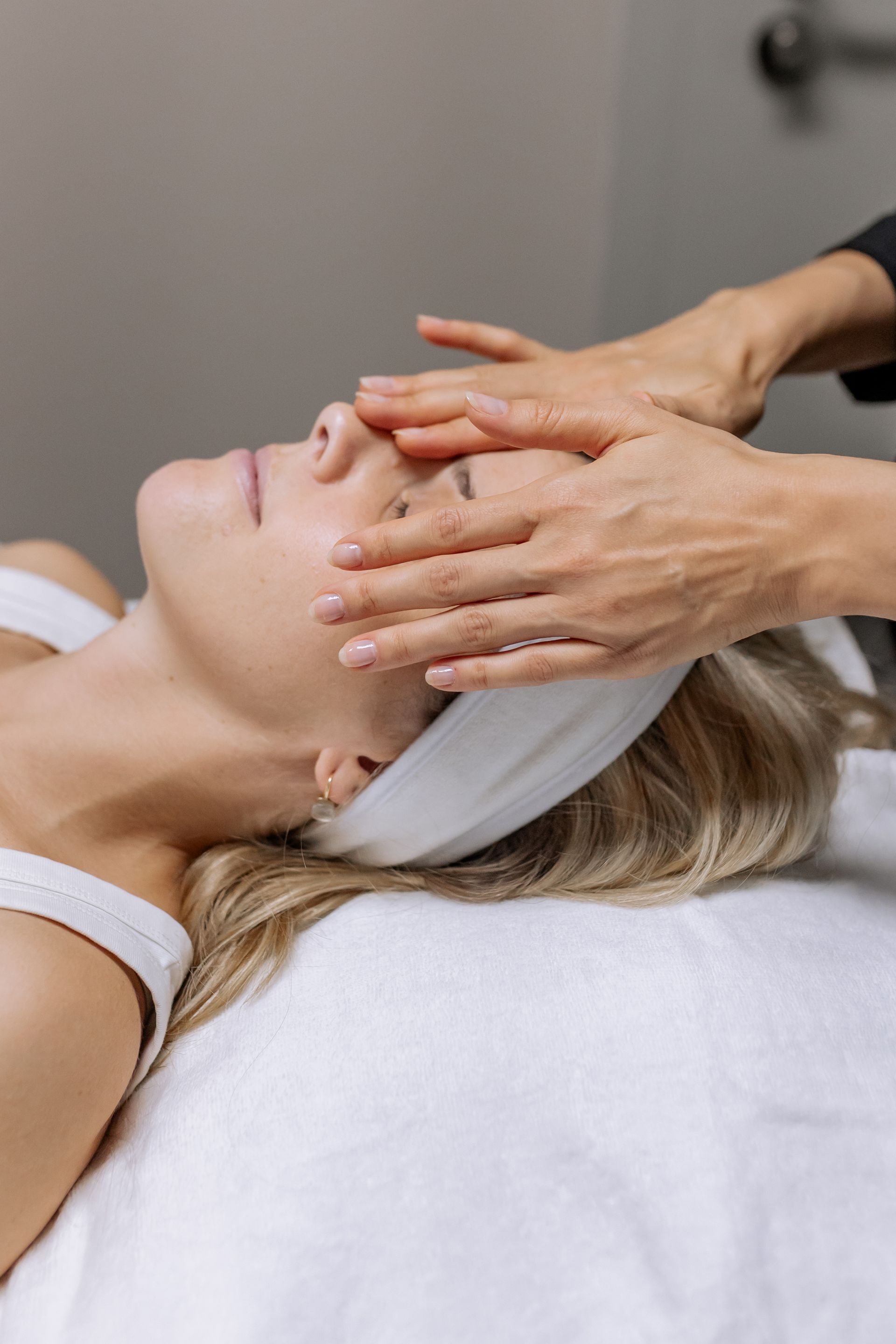 Eine Frau genießt eine Gesichtsbehandlung, während ihr Gesicht in einem Spa massiert wird.