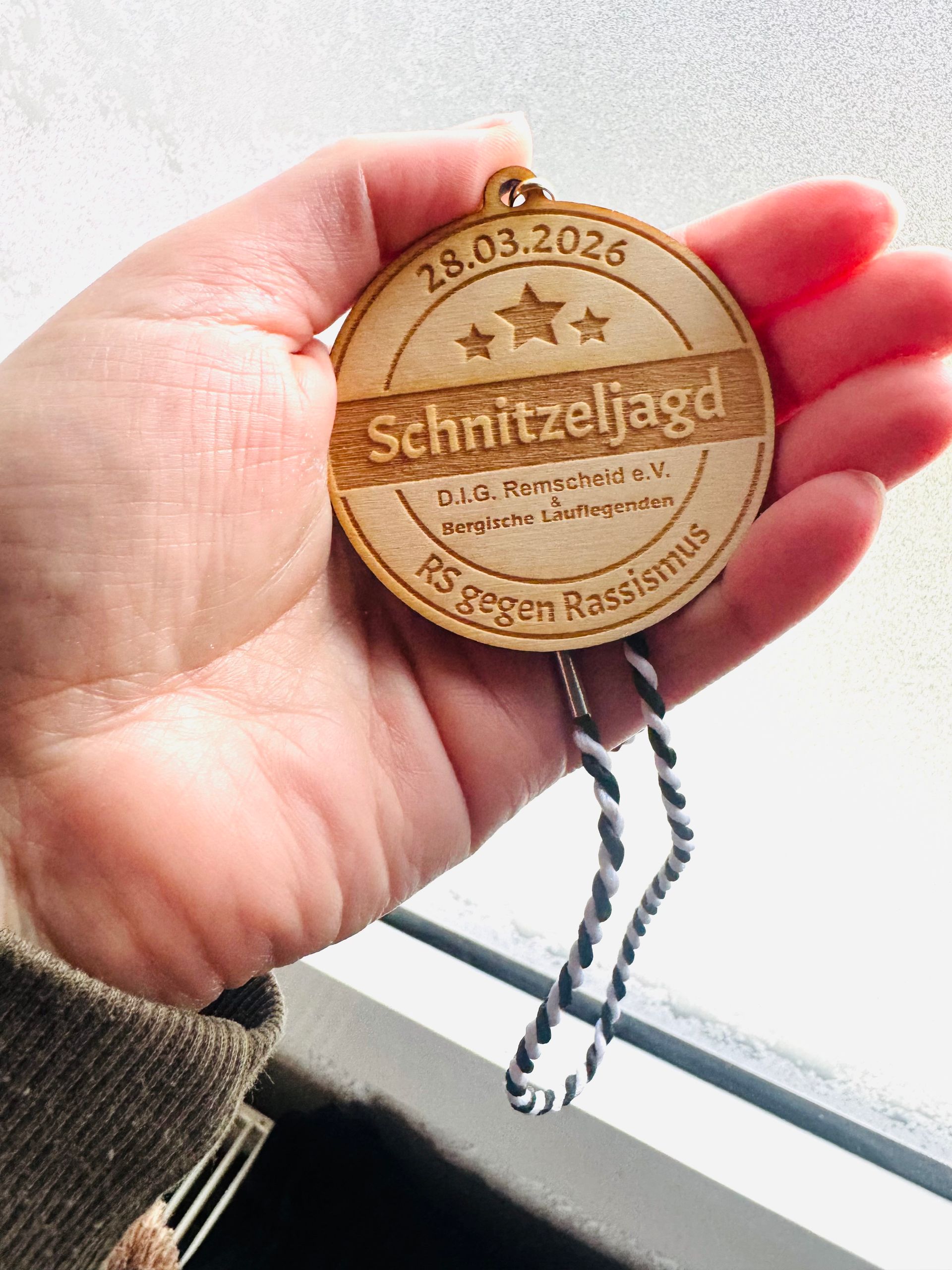 A hand holds a wooden medallion inscribed with 