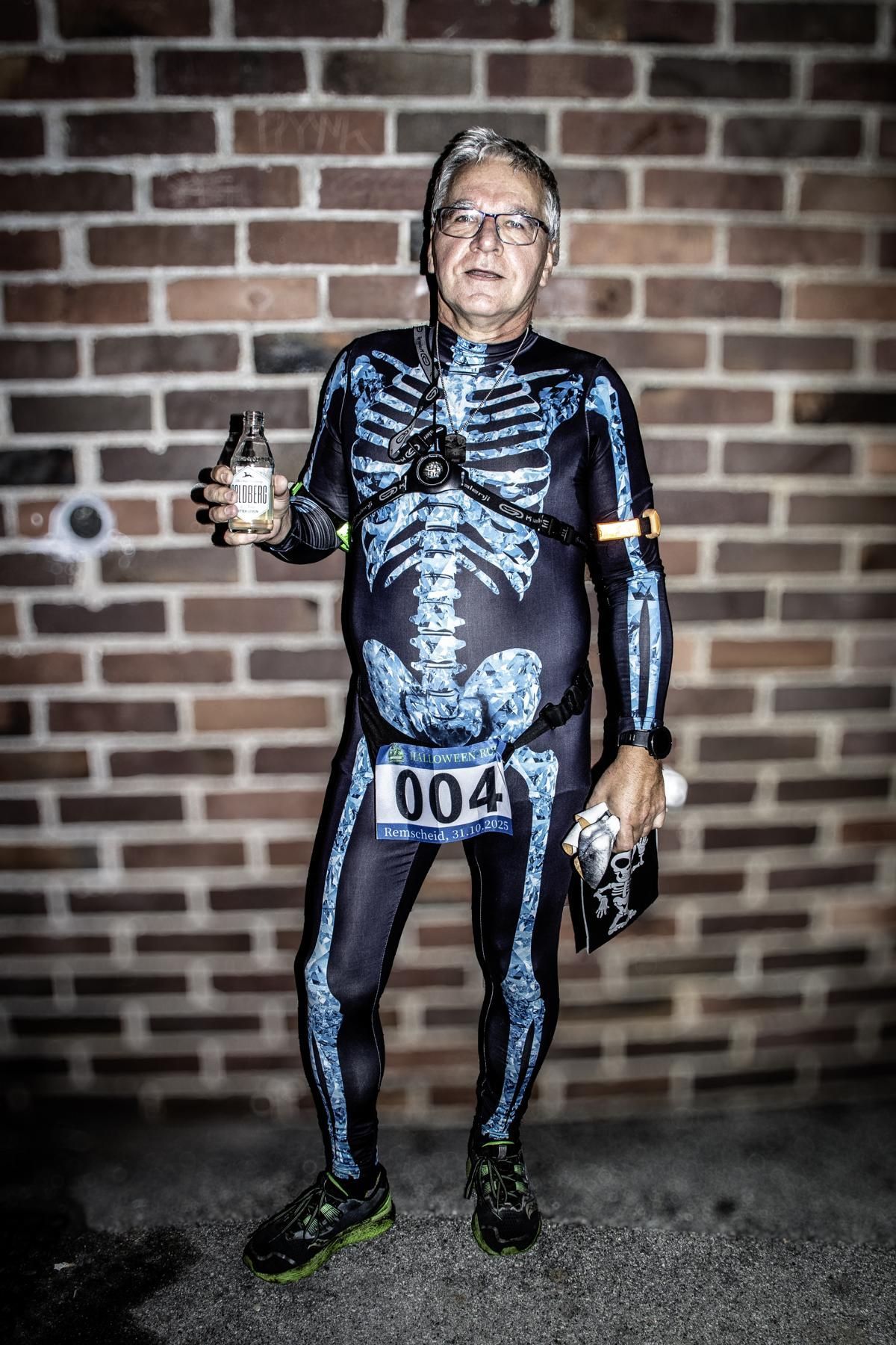 Eine Gruppe von Menschen in Kostümen jubelt an einem sonnigen Tag mit erhobenen Armen vor einem Gebäude.