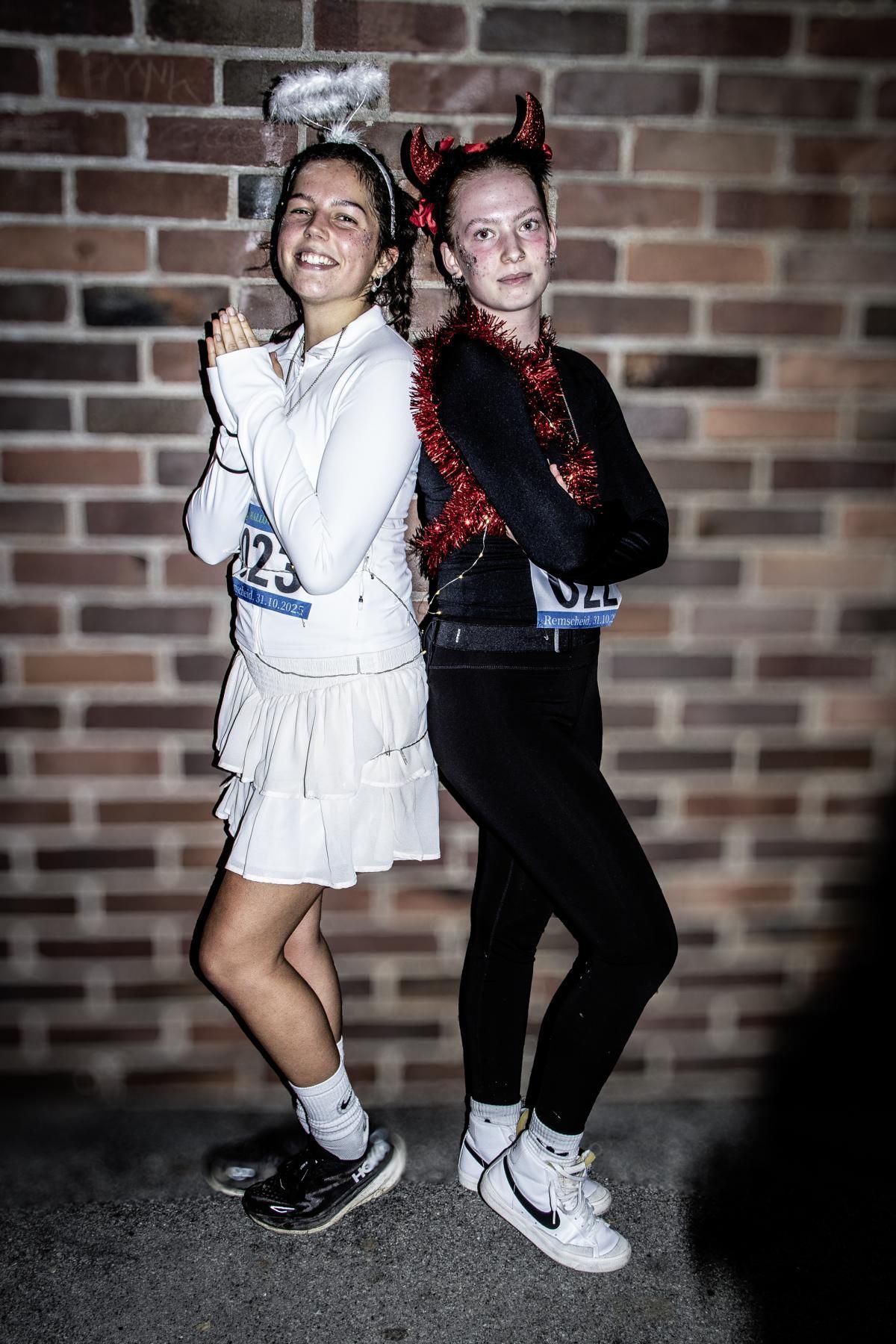 Eine Gruppe in Kostümen tanzt an einem sonnigen Tag vor einem Gebäude.