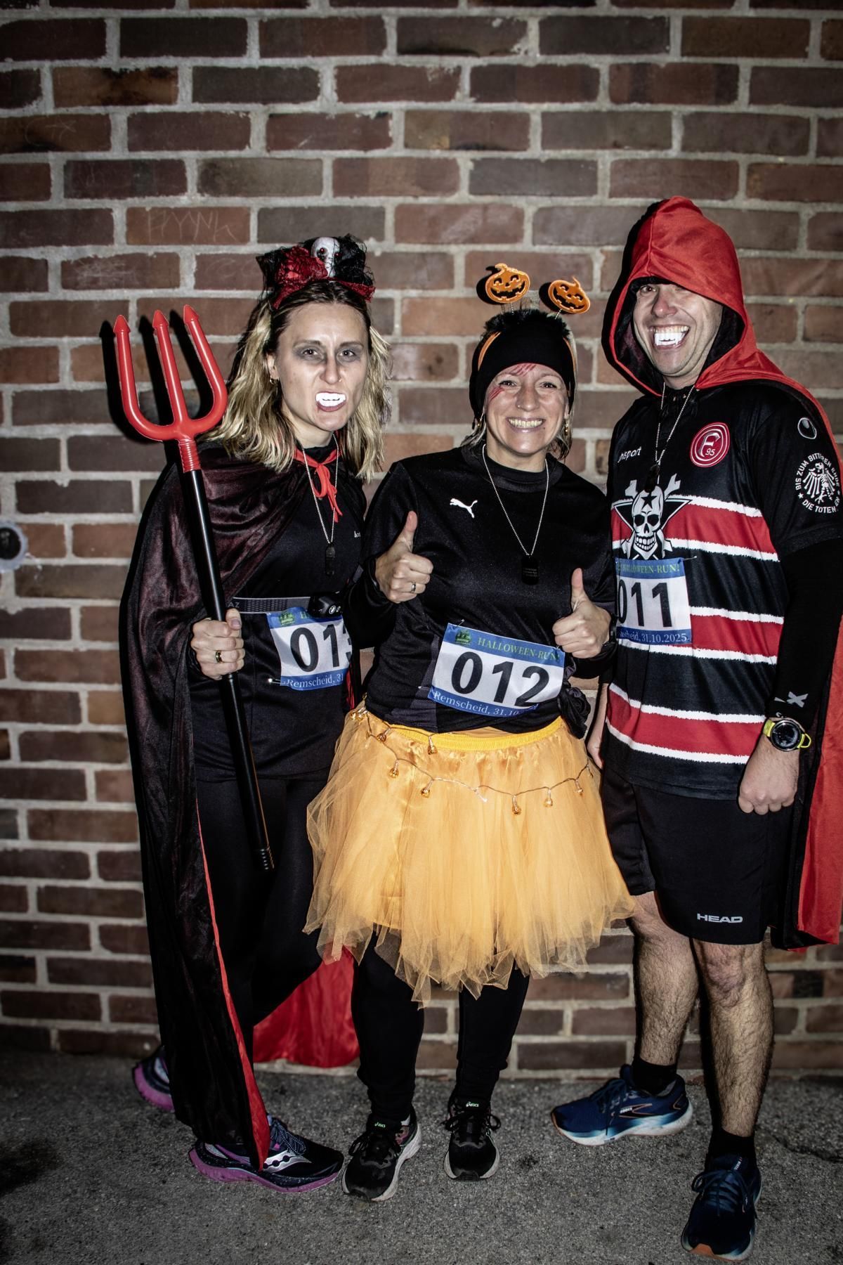 Vier lächelnde Personen in Kostümen posieren vor einem Gebäude.