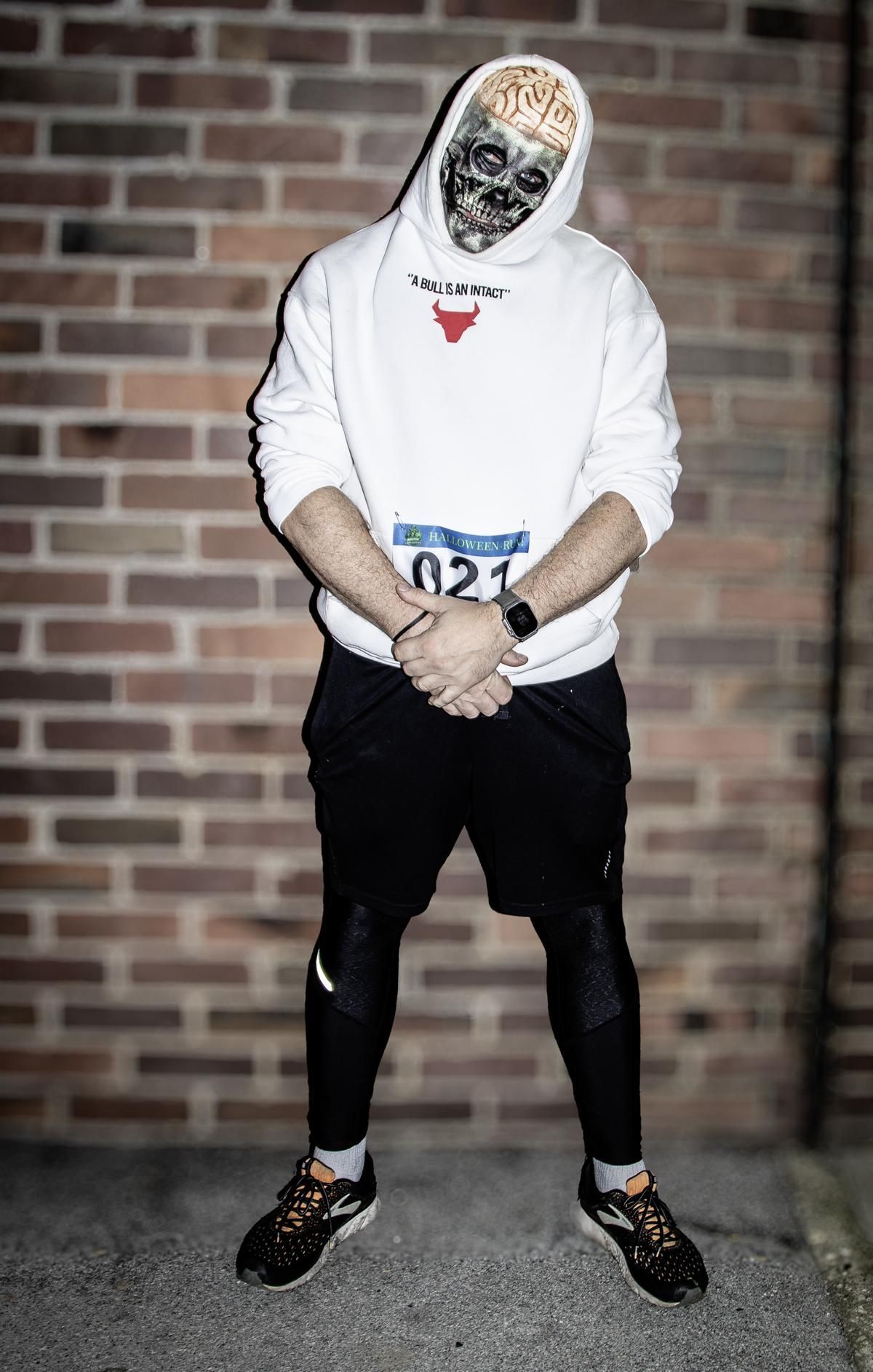 Frau im blauen Kostüm mit „M“ auf dem Hemd, läuft im Freien und lächelt.