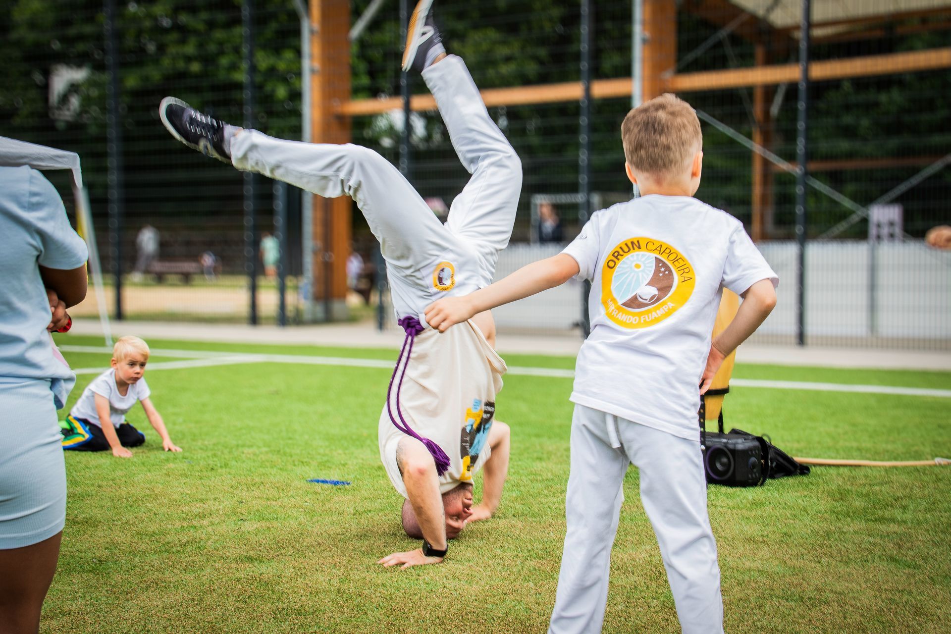 Kinder, die auf einer Rasenfläche in der Nähe eines Fußballtors Radschläge und Handstände machen.