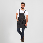 Un hombre lleva un delantal negro y una camisa blanca.
