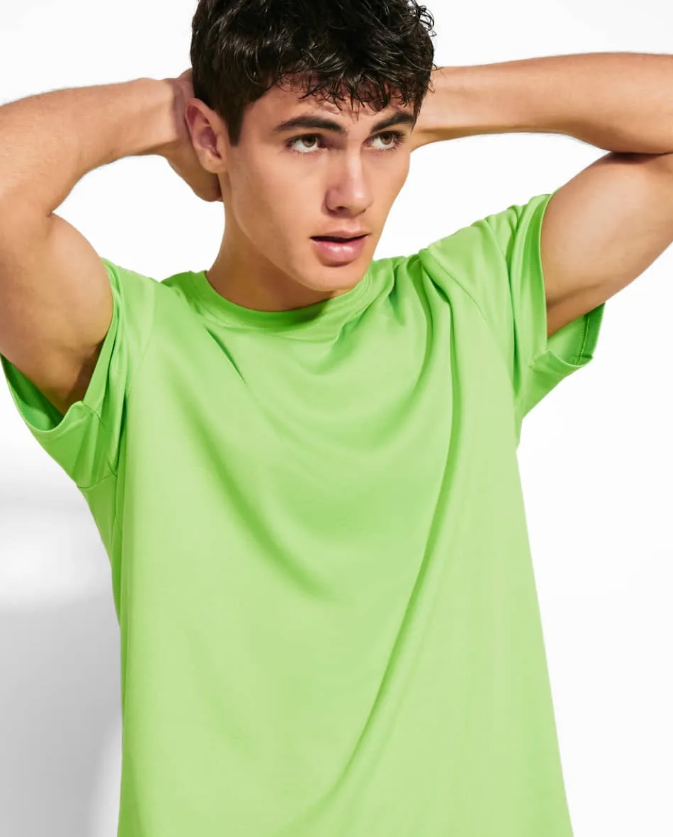 Un joven que lleva una camiseta verde brillante y tiene las manos detrás de la cabeza.