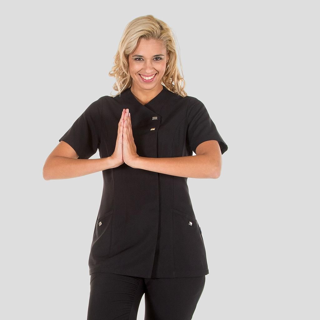 Una mujer que viste una camisa negra y pantalones negros está rezando con las manos juntas.