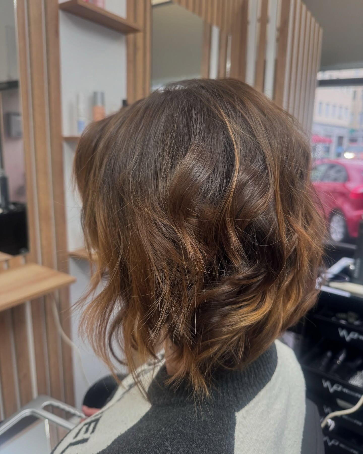 Chioma femminile castana di lunghezza media e piega ondulata.