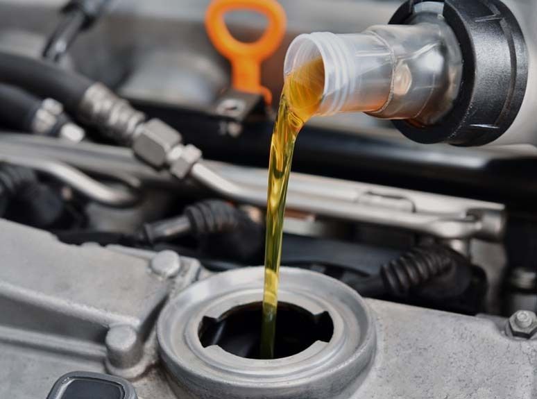 Eine Nahaufnahme einer Person, die Öl in einen Automotor gießt