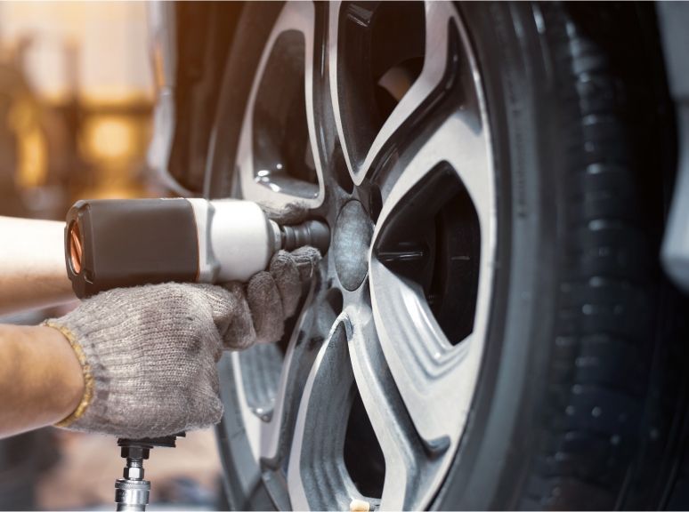 Eine Person wechselt mit einem Schraubenzieher einen Reifen an einem Auto.