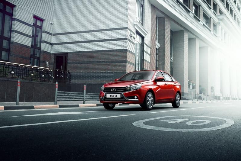 Ein rotes Auto parkt am Straßenrand vor einem Gebäude.