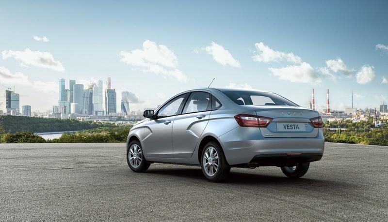 Ein silbernes Auto parkt am Straßenrand vor einer Stadt.