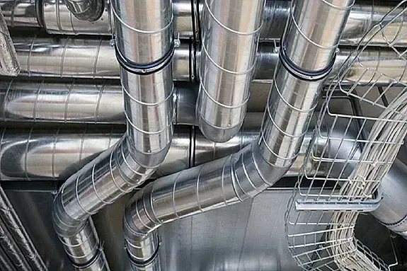 Un montón de tubos de metal cuelgan del techo de un edificio.