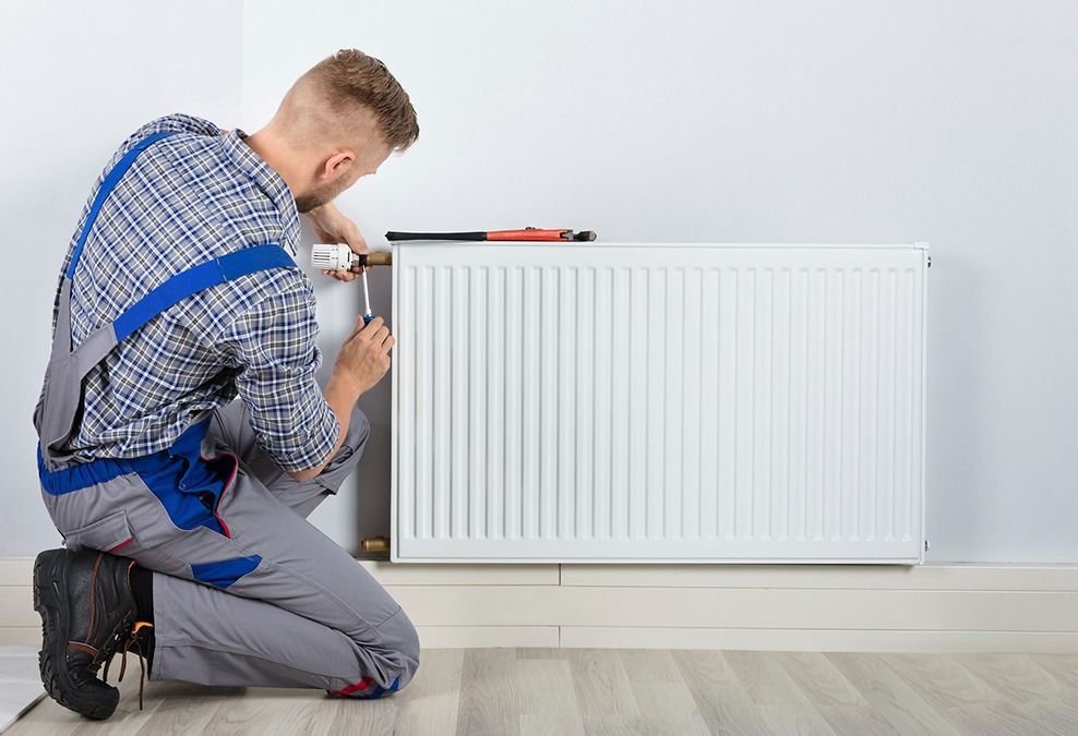 Un hombre está instalando un radiador en una habitación.