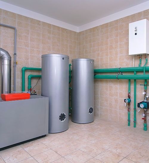 Una habitación con dos calentadores de agua y tuberías verdes.