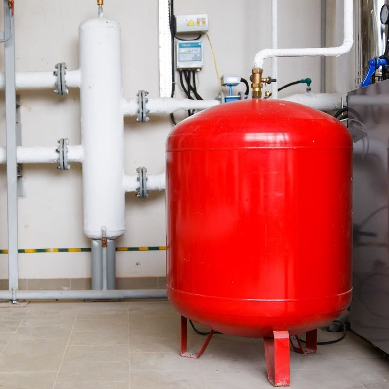 Un gran tanque rojo está en una habitación con tuberías.