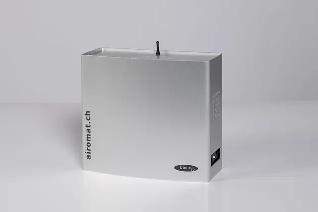 Silberner Lufterfrischer mit schwarzer Düse und Logo vor weißem Hintergrund.