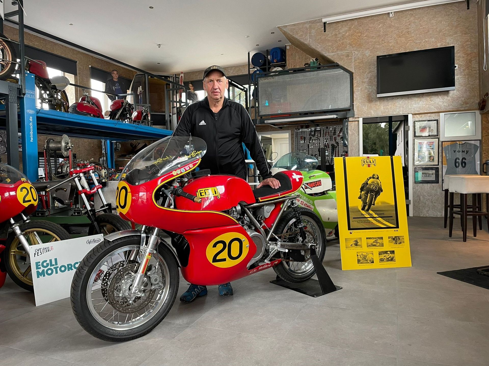 Ein Mann steht neben einem roten Motorrad mit der Nummer 20 darauf.