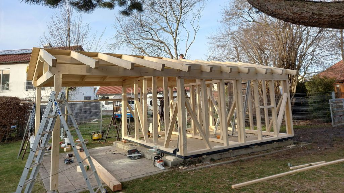 Im Bau befindliches hölzernes Dachgerüst vor blauem Himmel mit flauschigen Wolken.