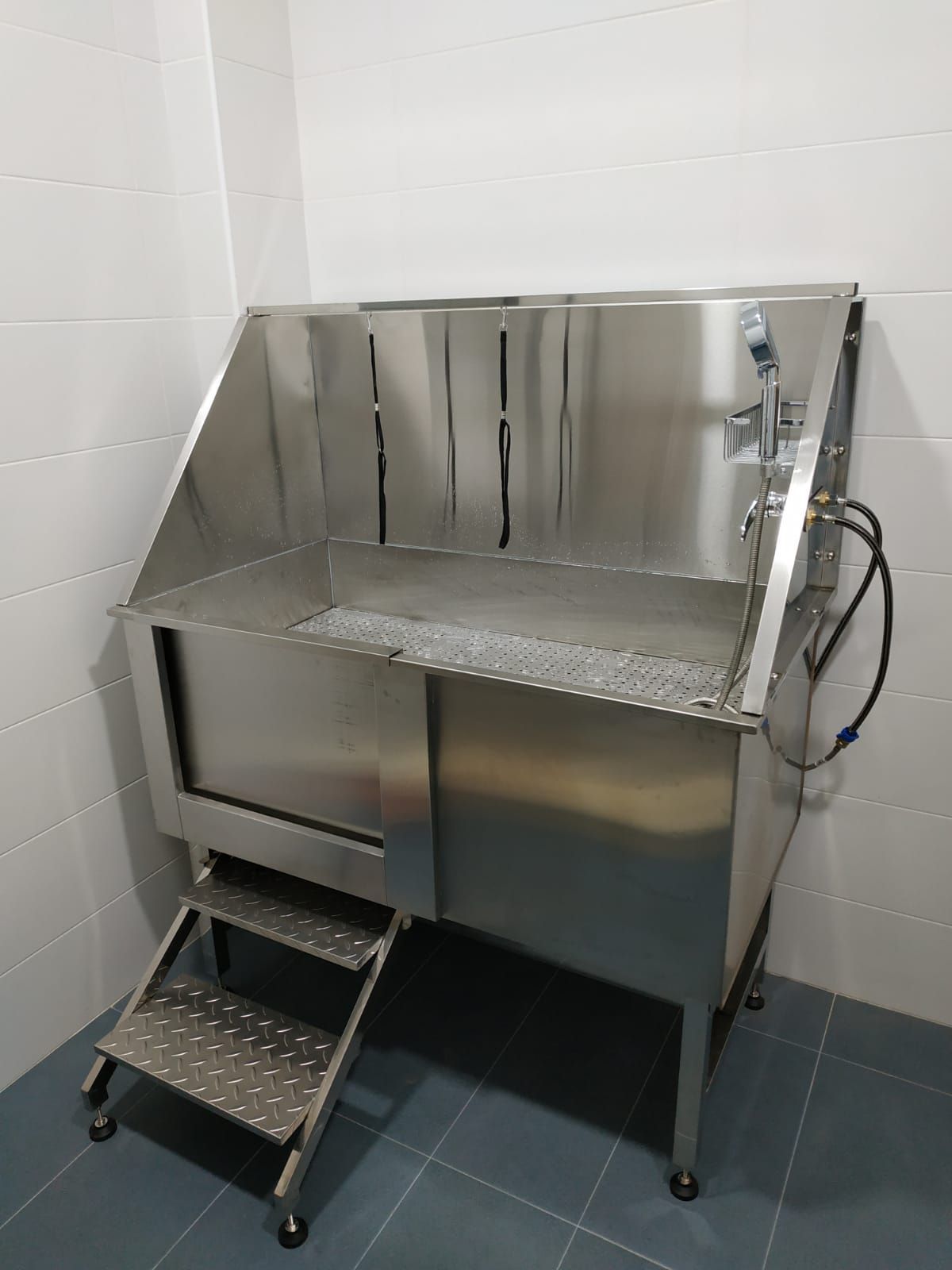 Una bañera para perros de acero inoxidable con escaleras en un baño.