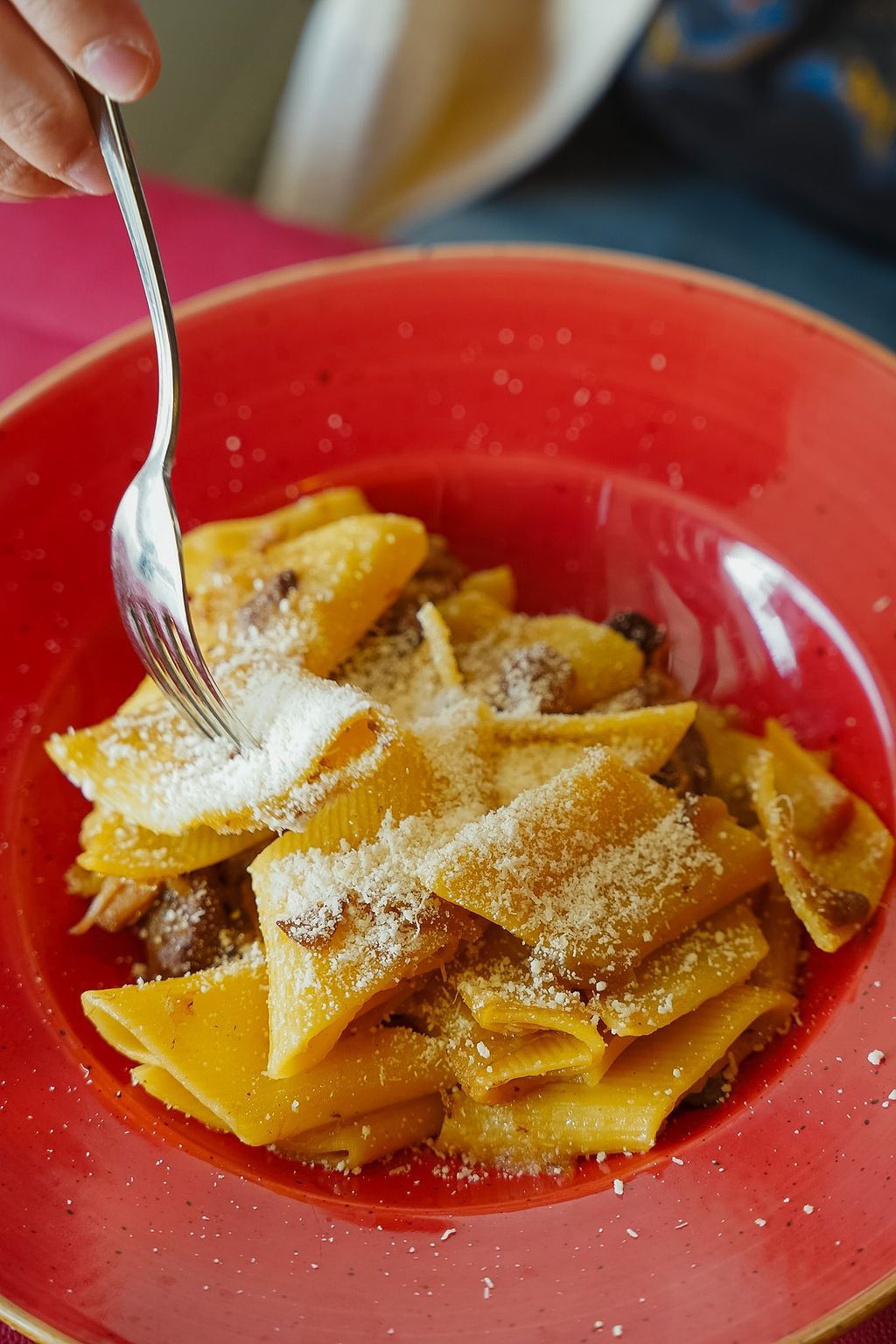 Una ciotola di pasta con olive e capperi su un tagliere di legno.