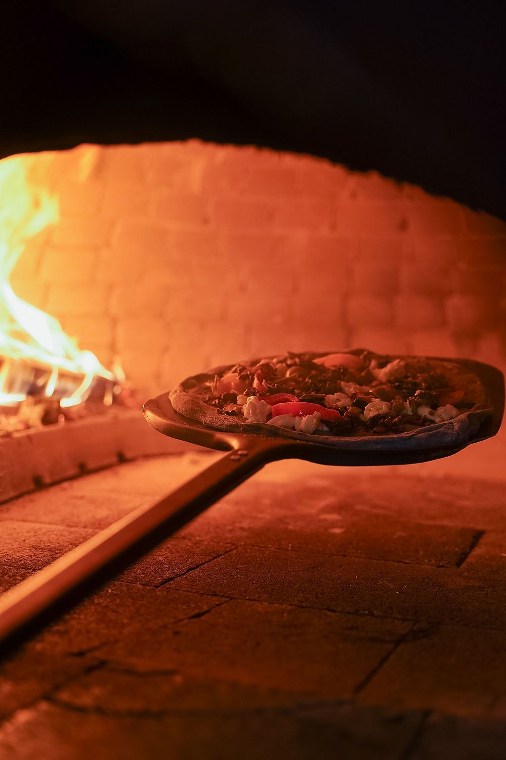 Una pizza è appoggiata su un piatto blu su un tavolo.