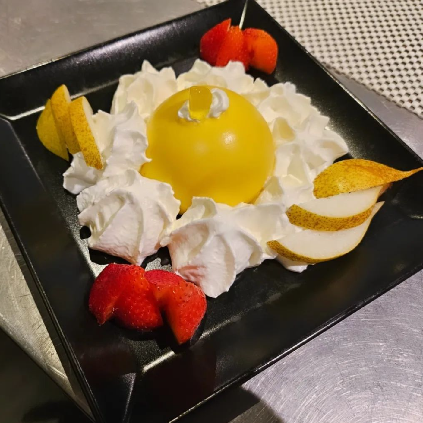 Un piatto di cibo è appoggiato su un tavolo accanto a un bicchiere di vino.