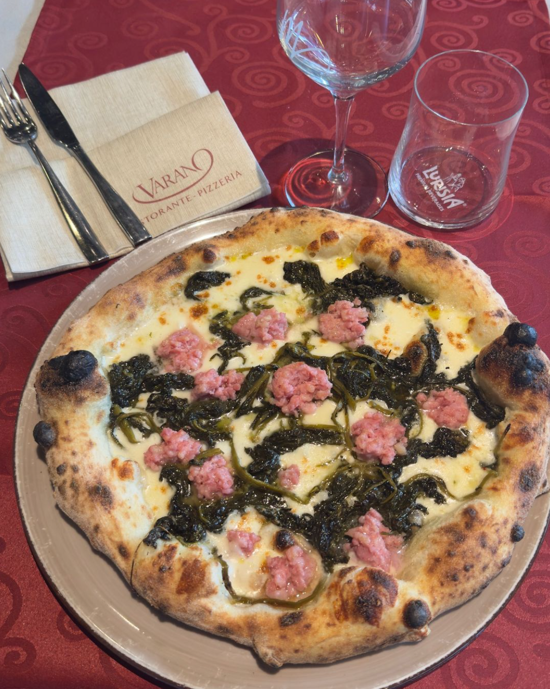 Un piatto rosso guarnito con tagliatelle, gamberi, cozze e granchio.