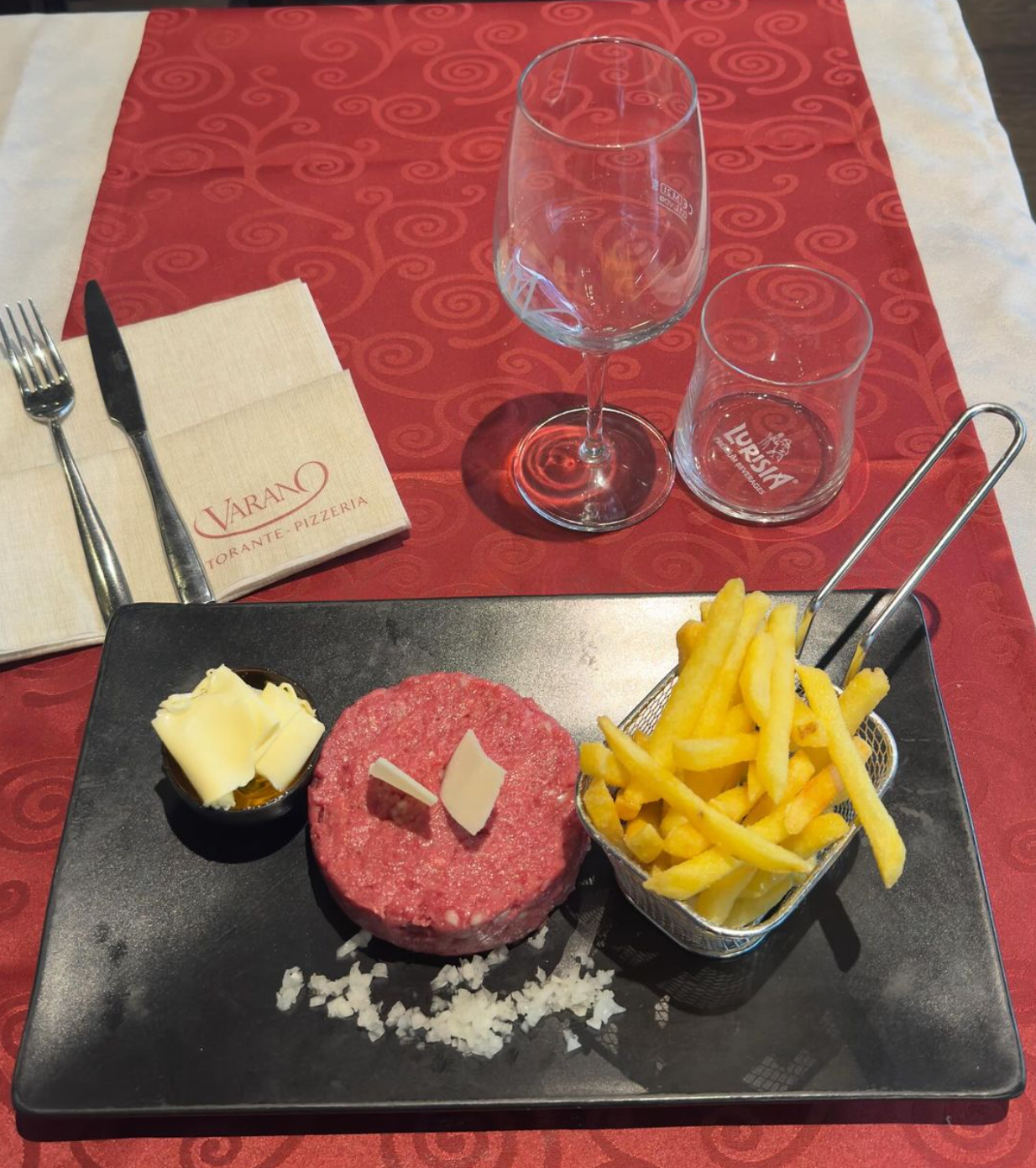 Un piatto di cibo con un hamburger e patatine fritte su un tavolo.