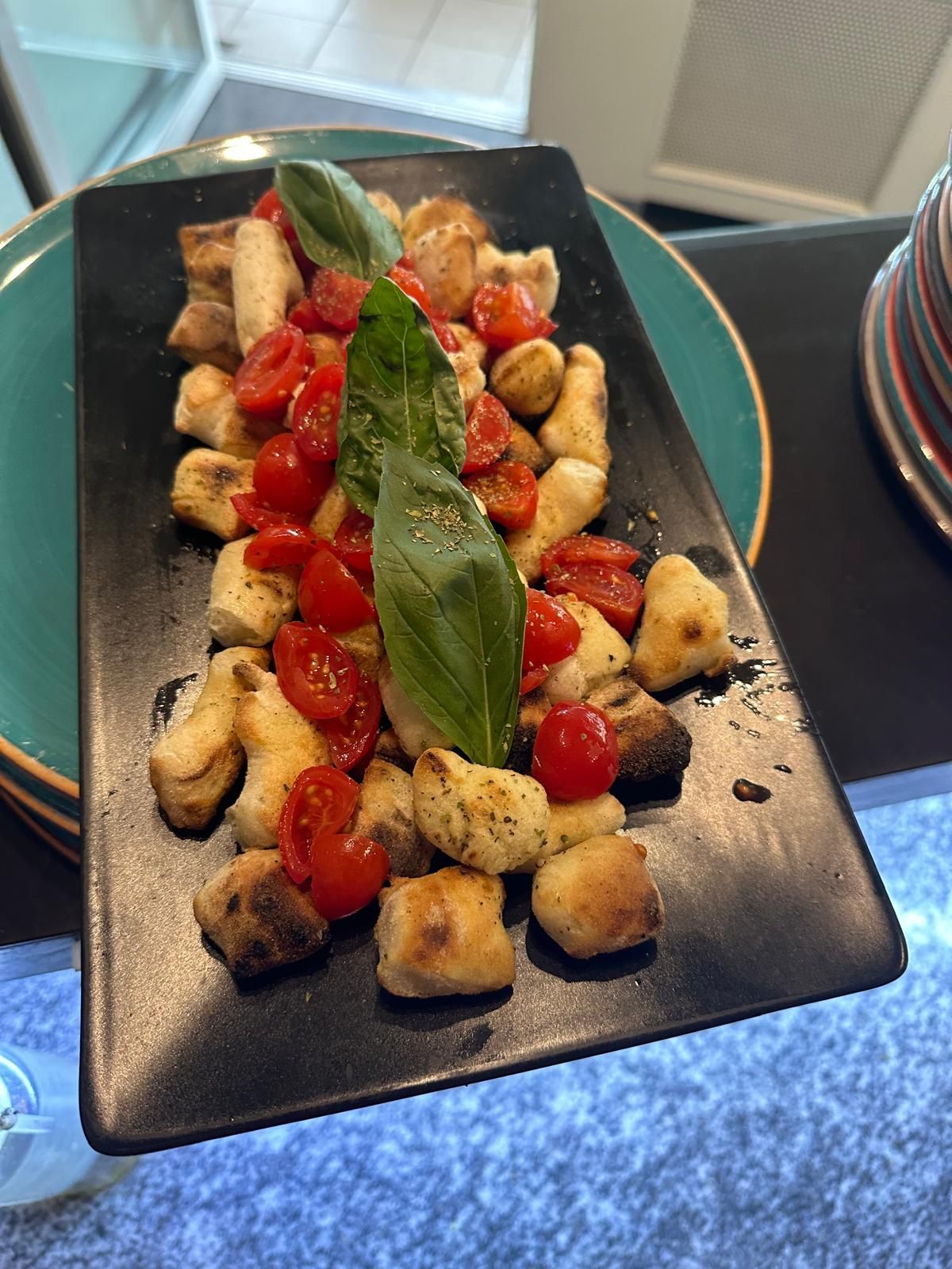 Un piatto di cibo è appoggiato su un tavolo accanto a un bicchiere di vino.