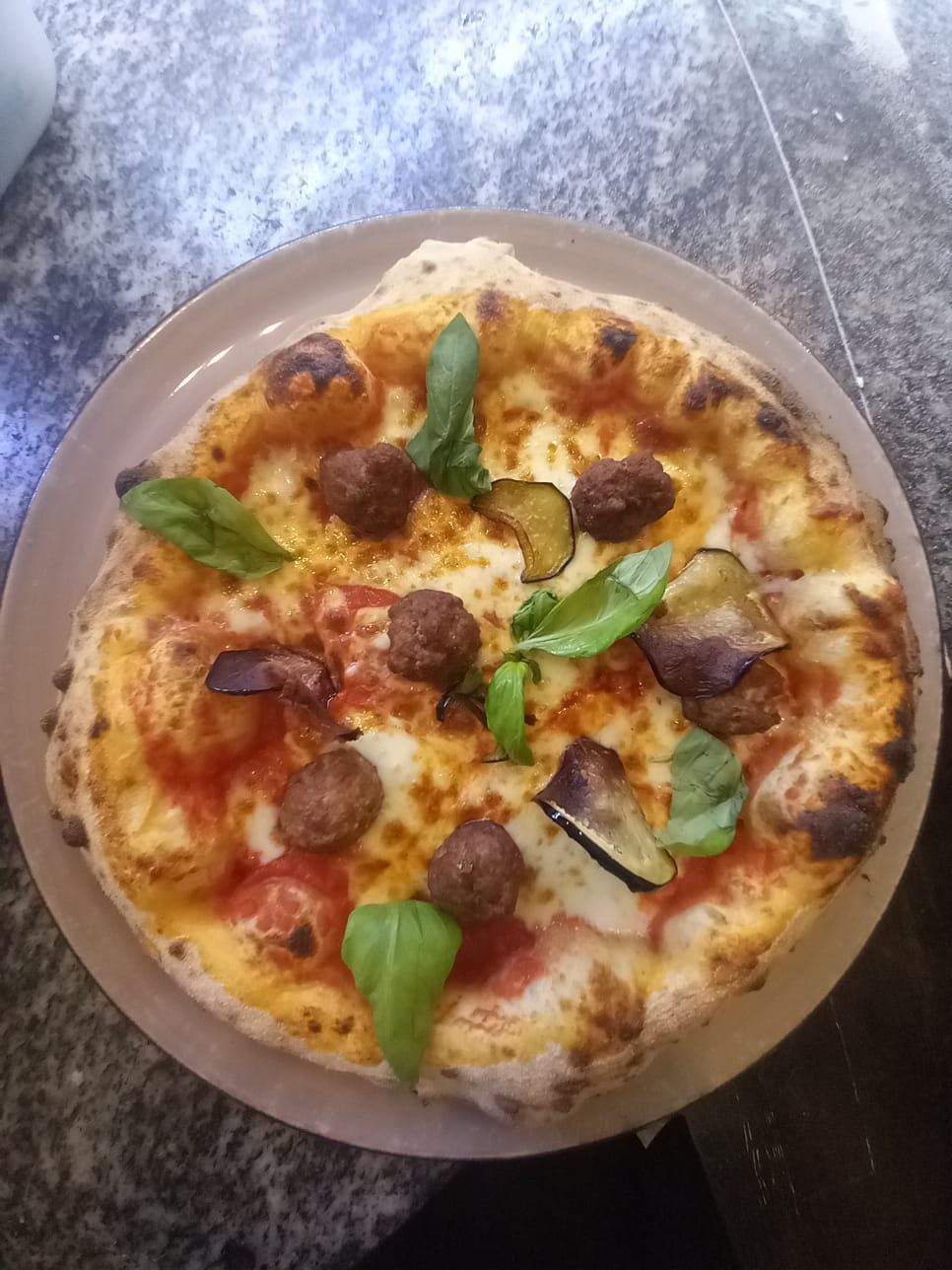 Un piatto di cibo è appoggiato su un tavolo accanto a un bicchiere di vino.