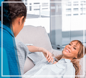 Una mujer está tumbada en un sofá hablando con un médico.