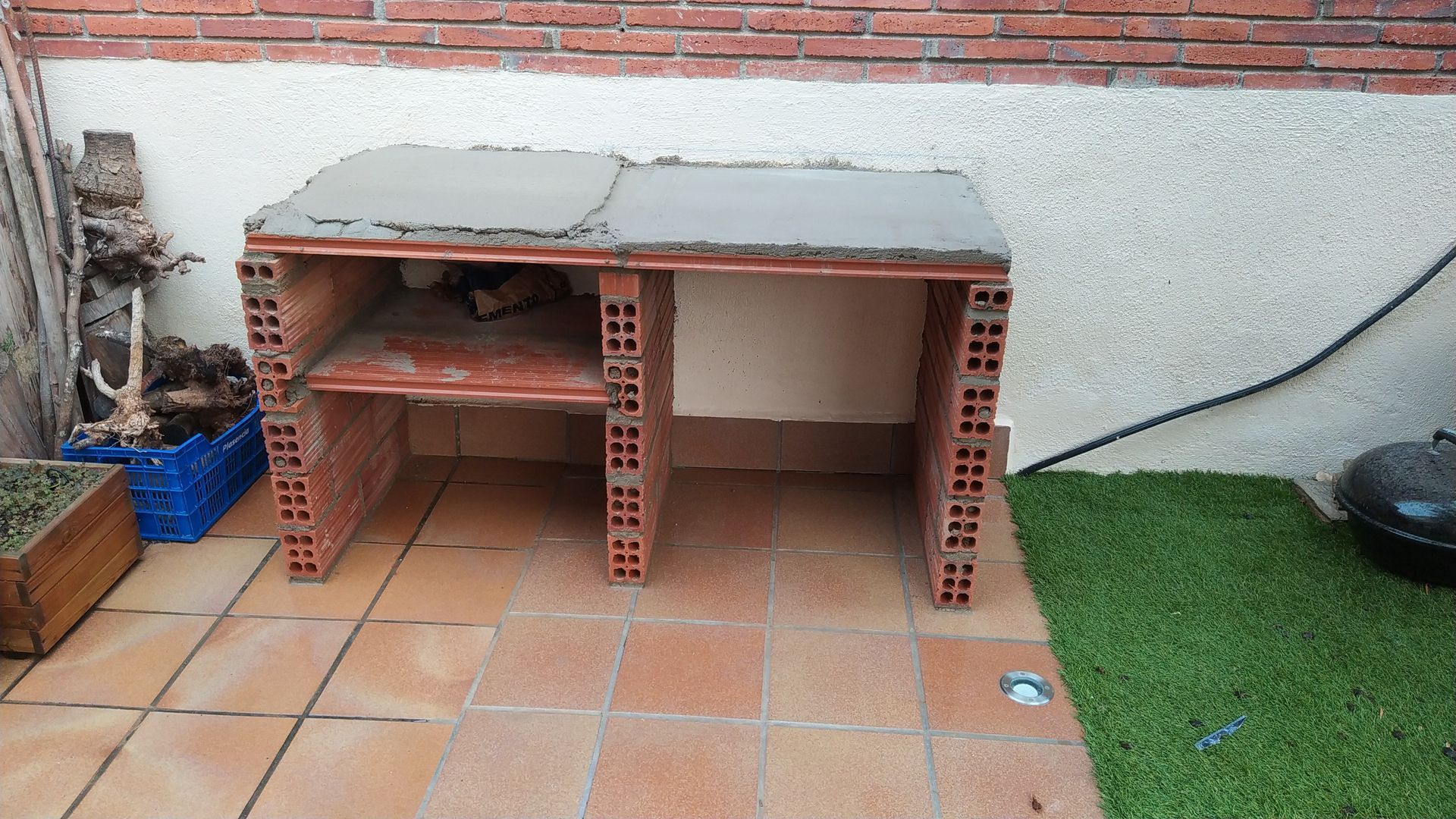 Una mesa de ladrillo está colocada sobre un suelo de baldosas al lado de una pared de ladrillos.