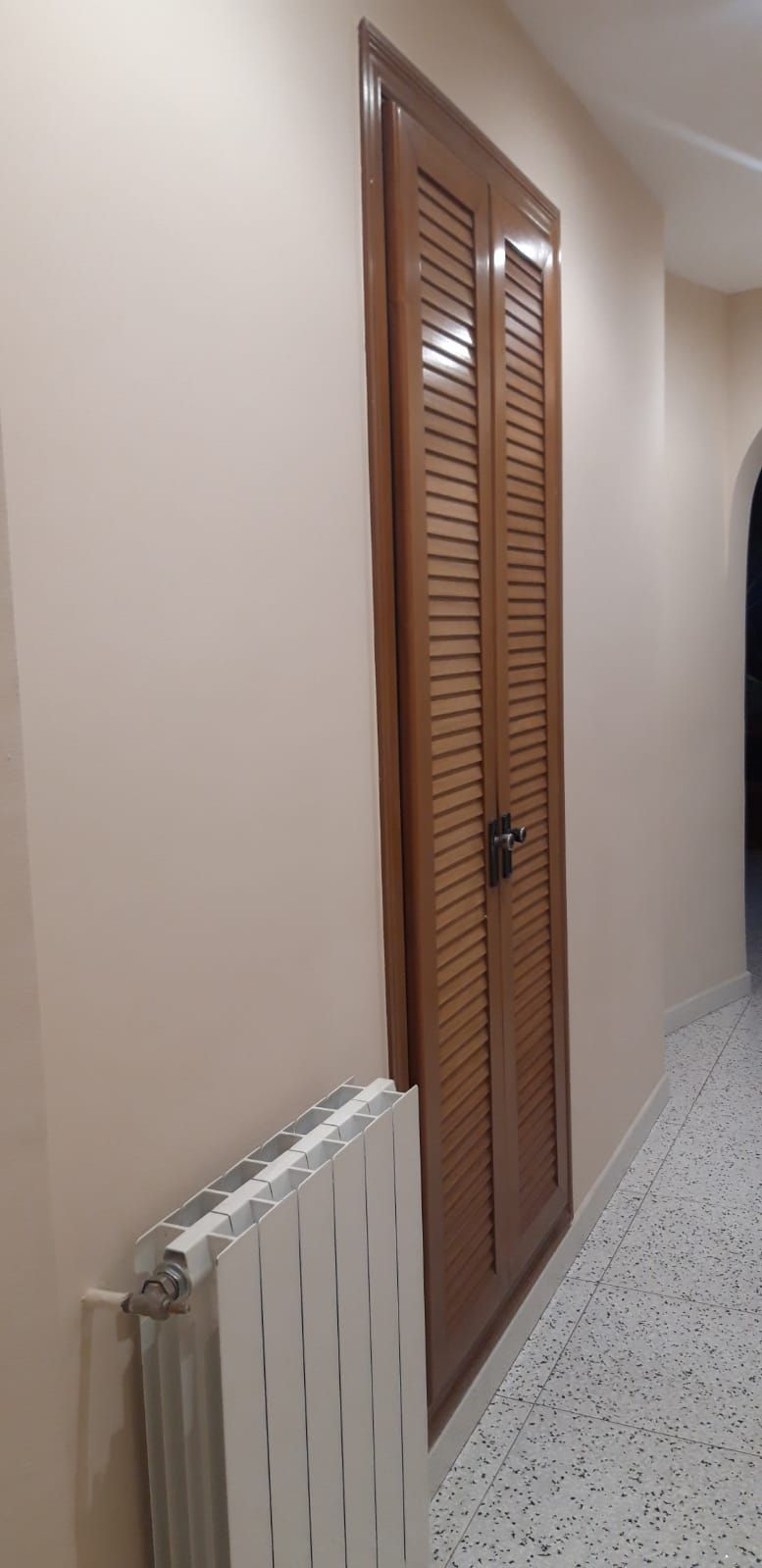 Hay un radiador al lado de una puerta en un pasillo.