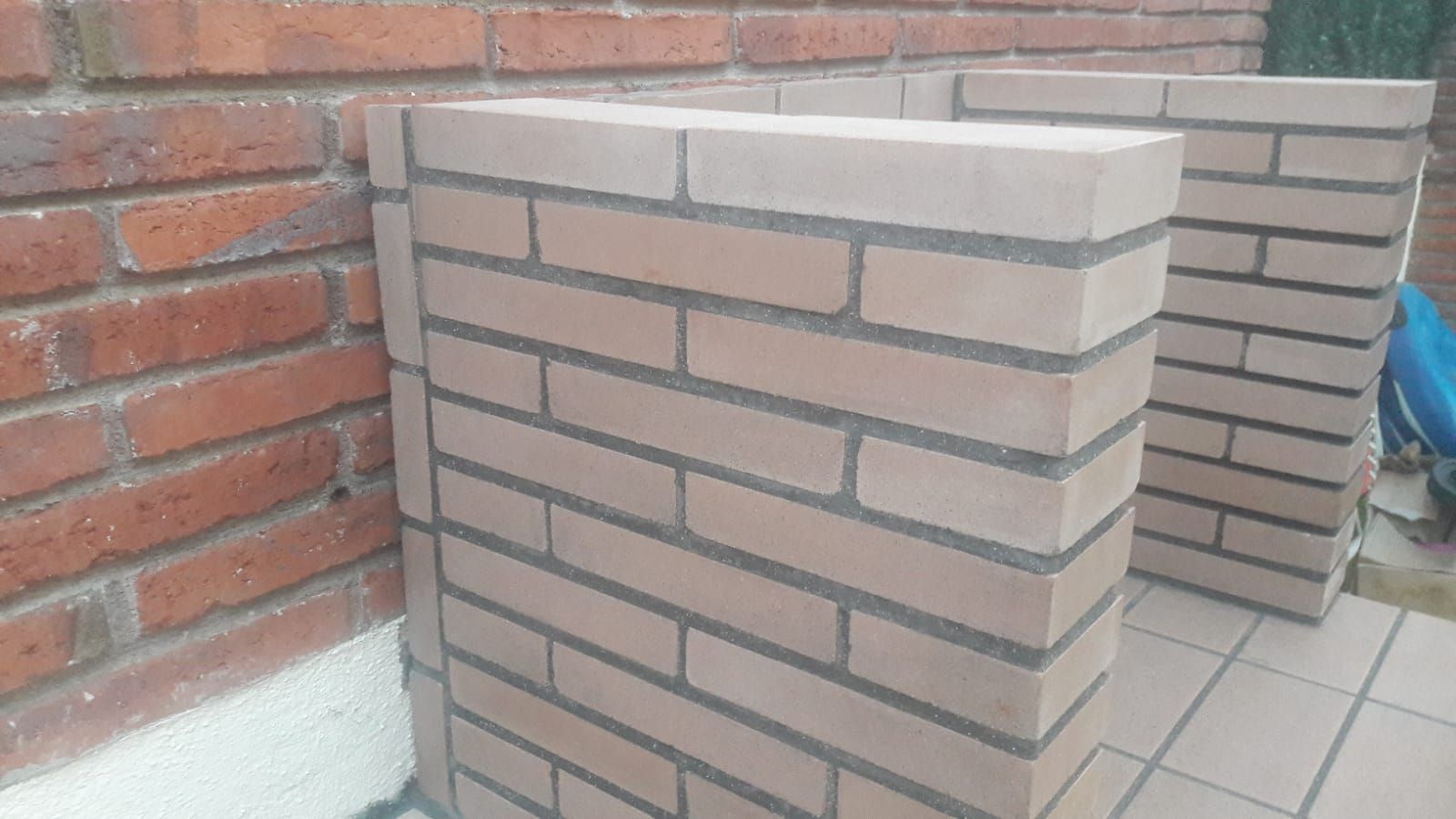 Dos pilares de ladrillo están uno al lado del otro frente a una pared de ladrillos.
