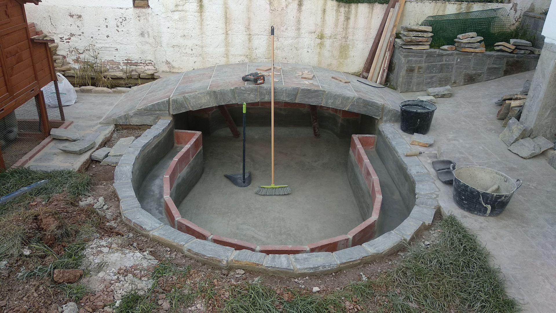 Se está construyendo una piscina en un patio trasero con una escoba en el medio.