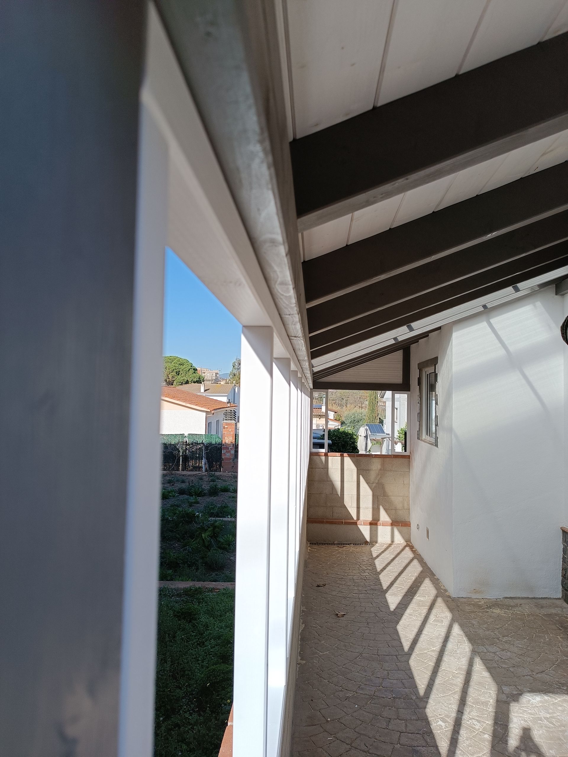 Un largo pasillo que conduce a un balcón con techo.