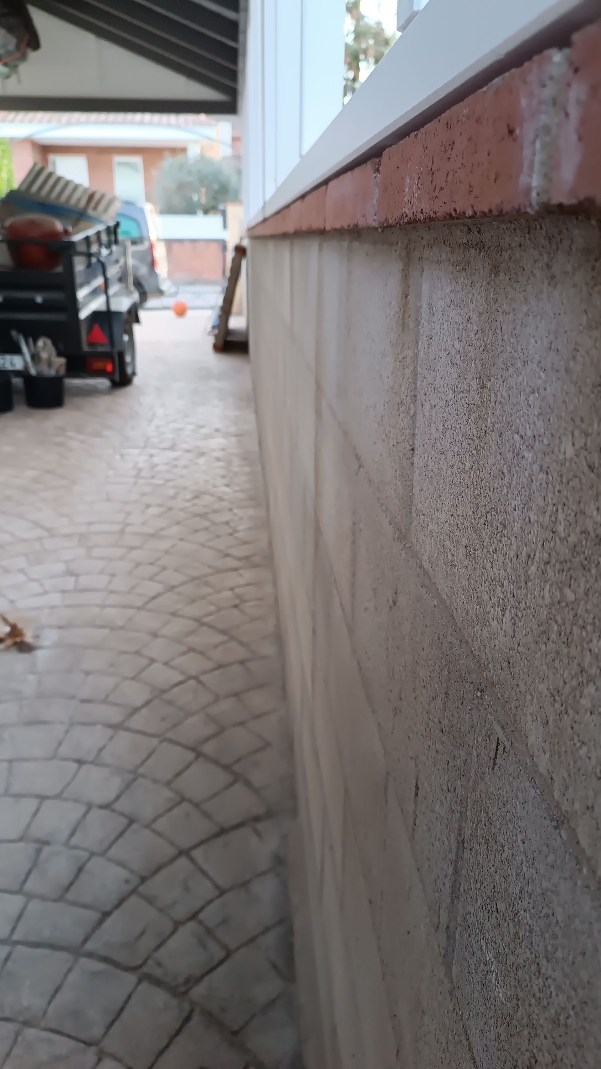 Un coche está aparcado en una entrada junto a un muro.