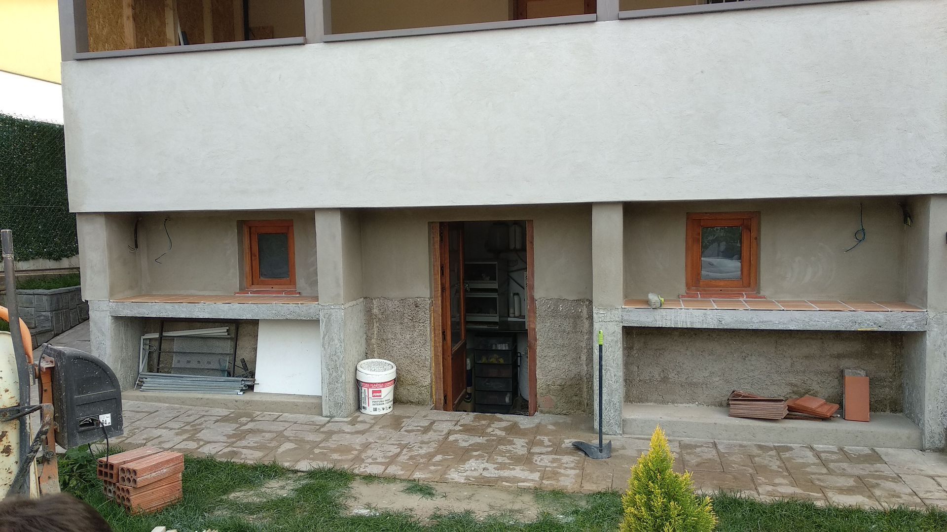 Un edificio en construcción con un cubo de pintura en el suelo frente a él.