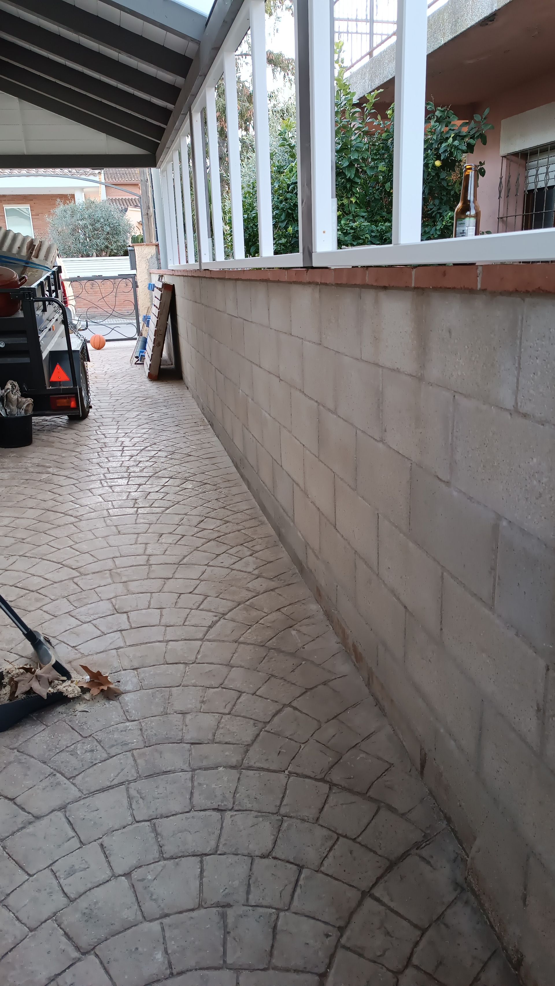 Una pasarela de ladrillos que conduce a un garaje con una escoba en primer plano.