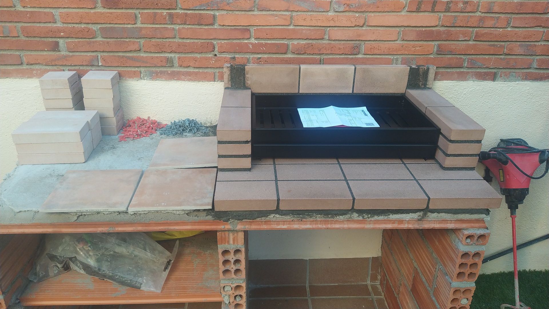 Se está construyendo una barbacoa de ladrillos delante de una pared de ladrillos.