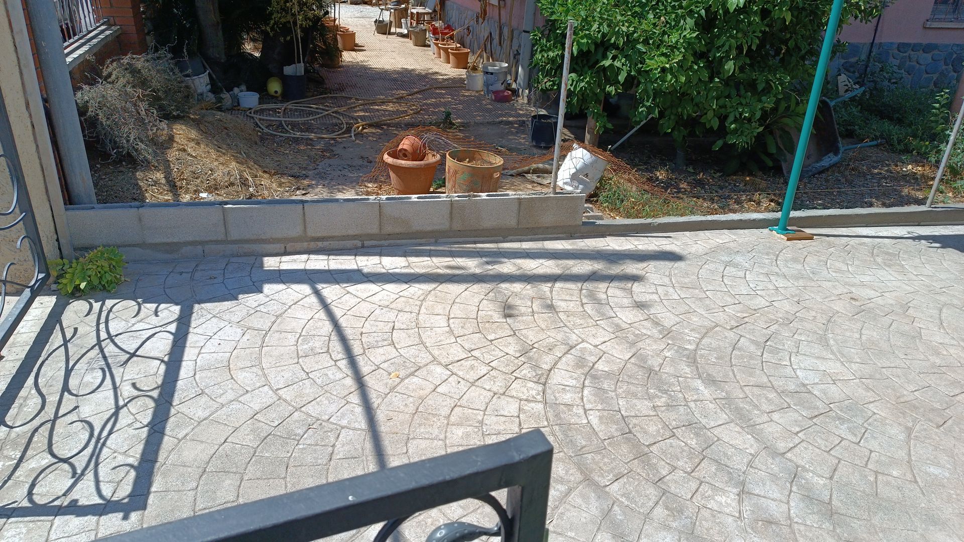 Una pasarela de hormigón que conduce a una casa con una puerta de hierro forjado.