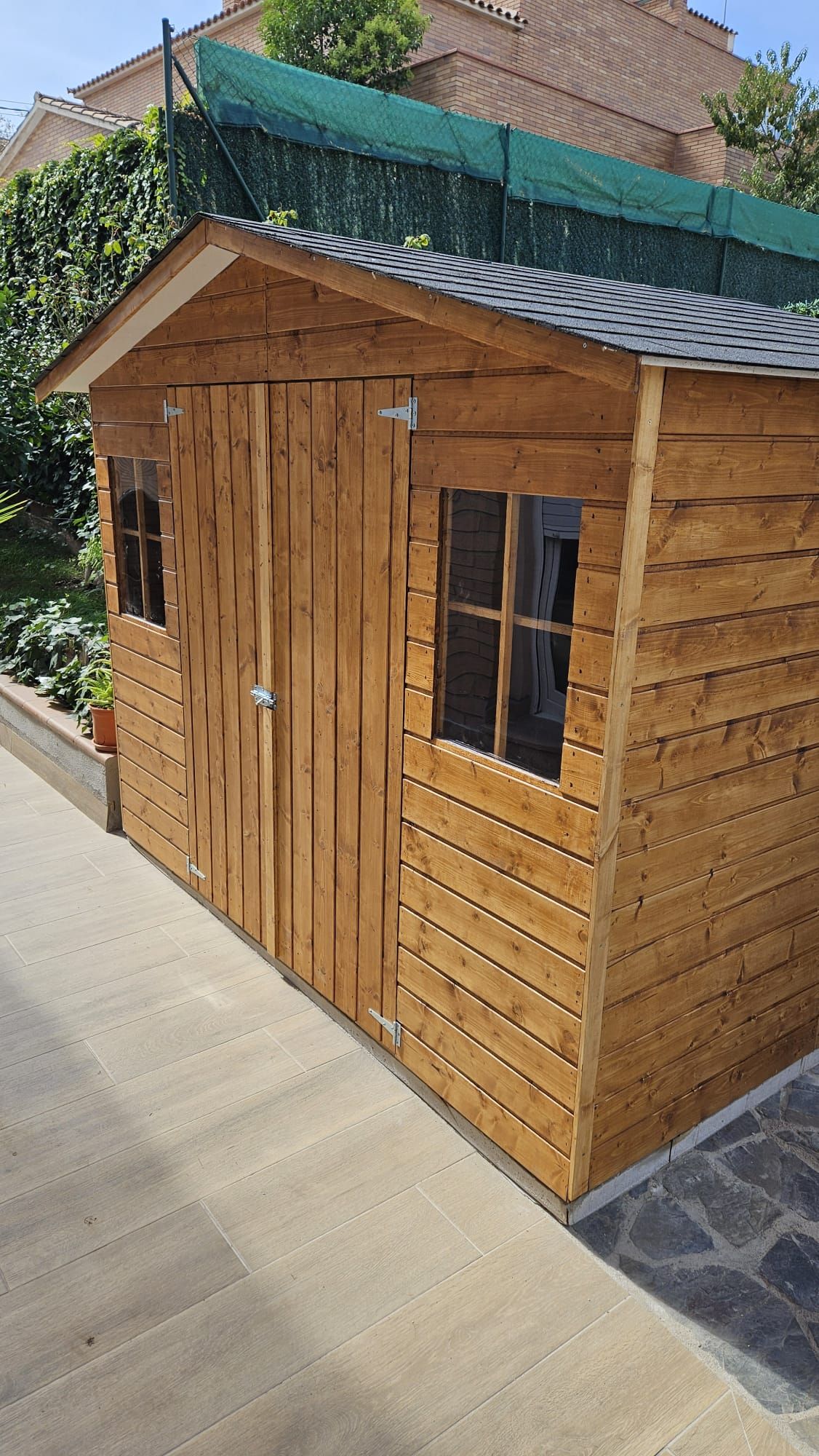Un cobertizo de madera con techo y ventanas está al costado de una carretera.