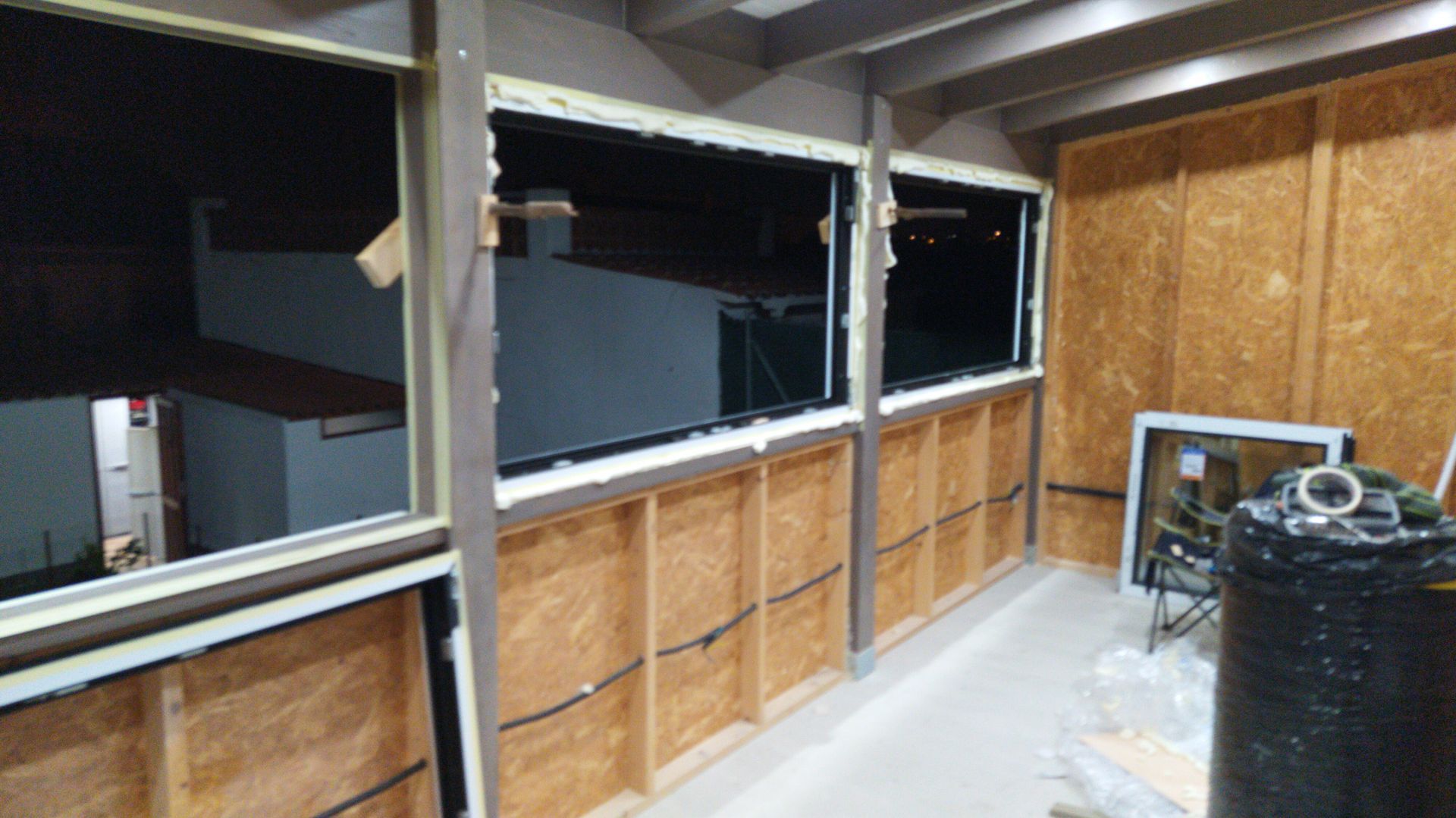 Una habitación con muchas ventanas y un barril negro.