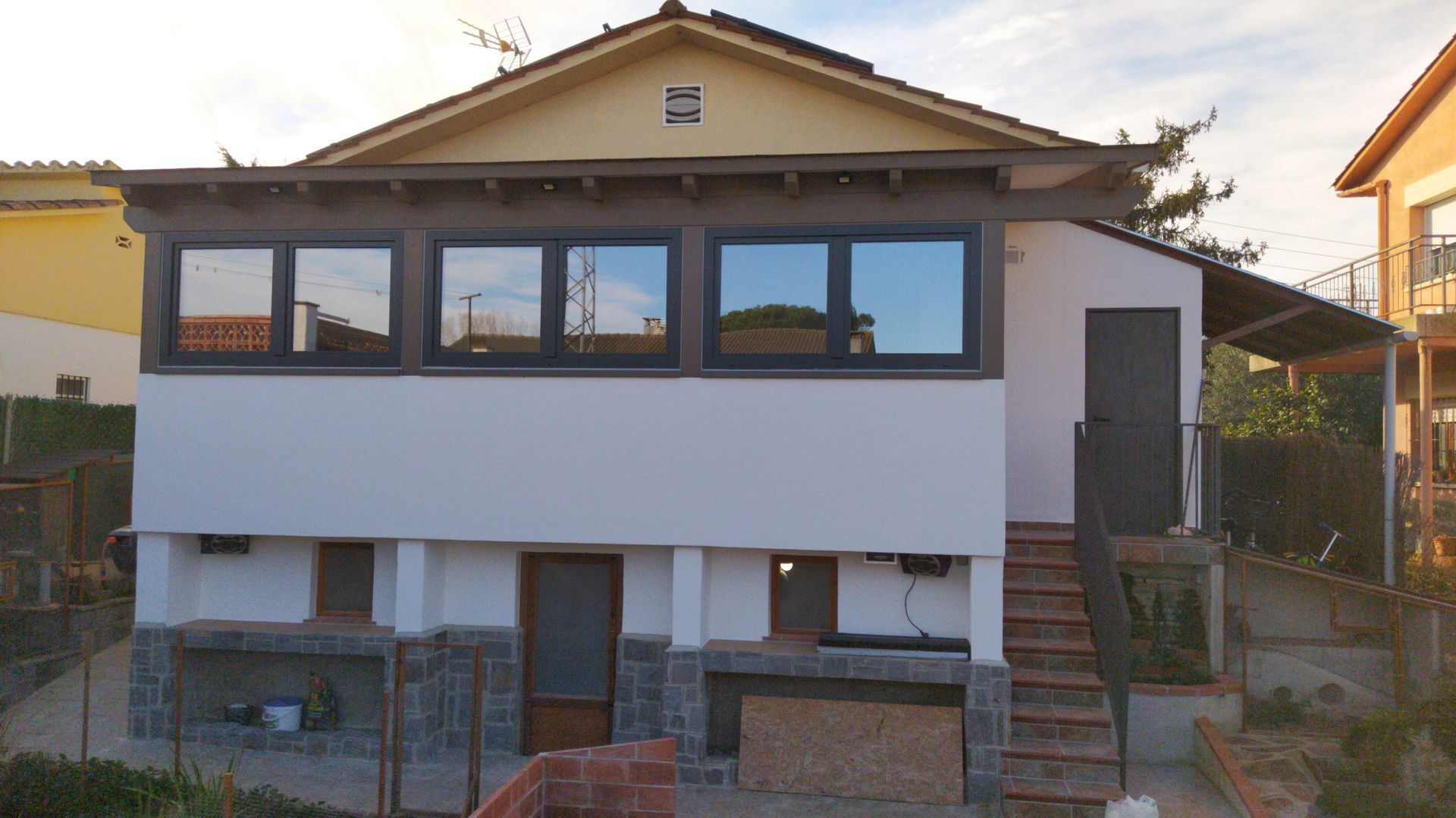 Una casa blanca con techo amarillo y muchas ventanas