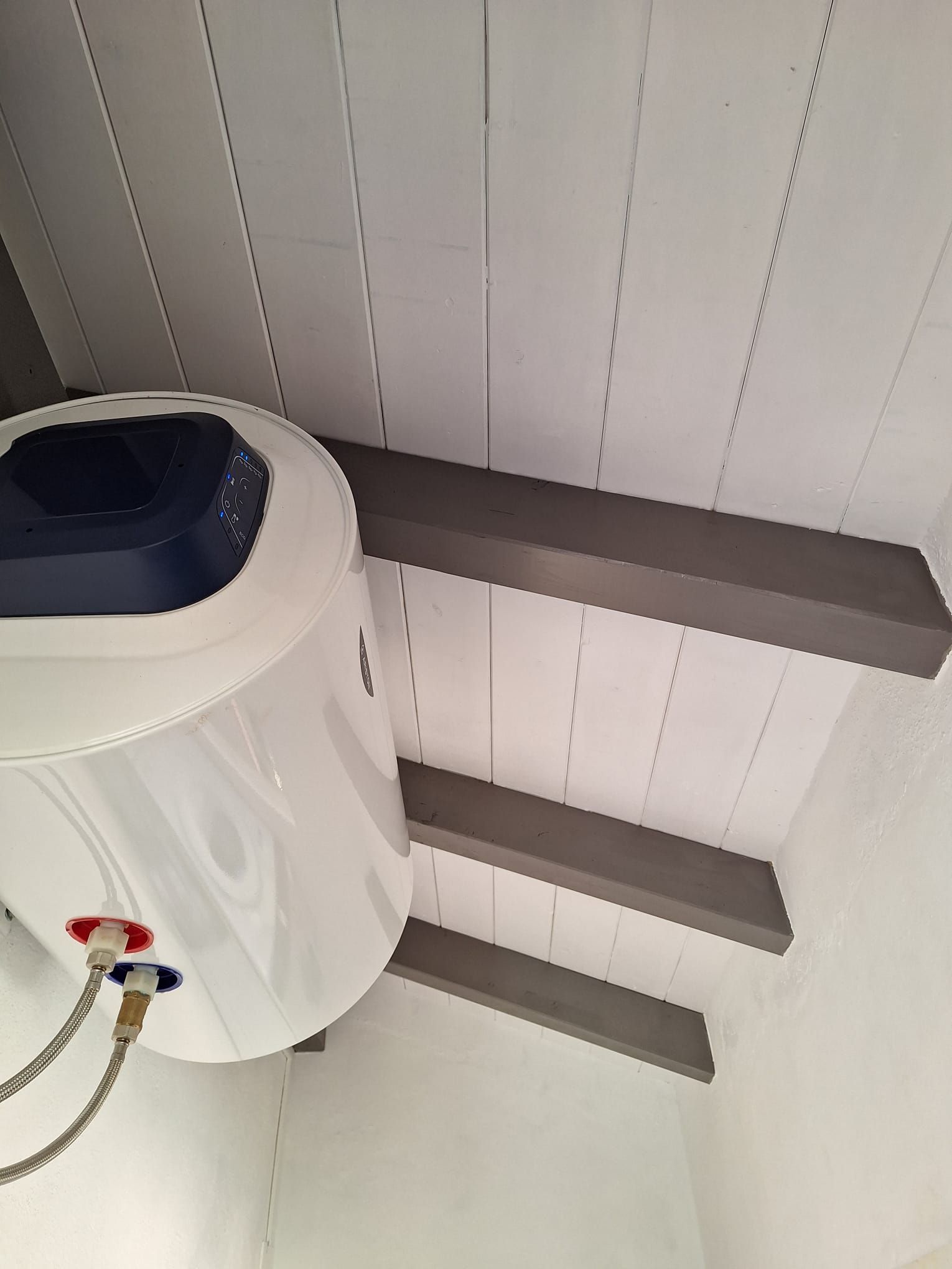 Un calentador de agua blanco cuelga del techo.