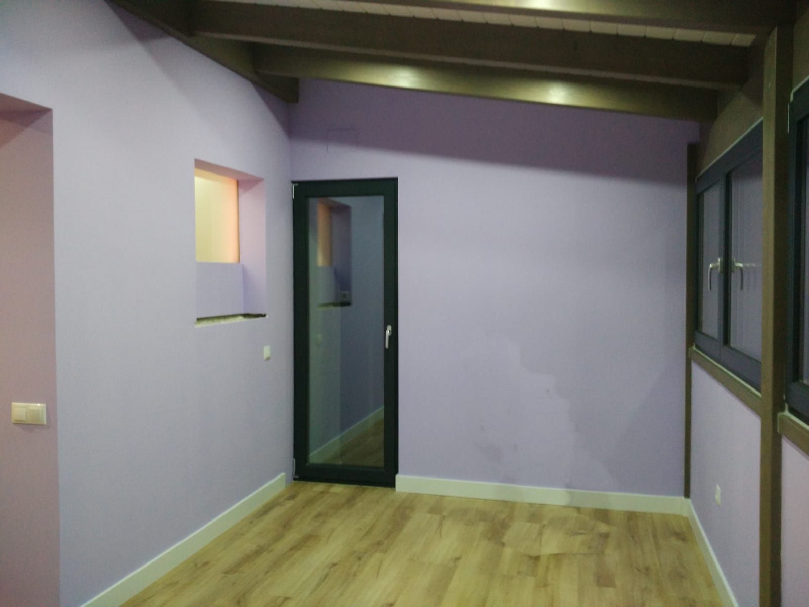 Una habitación con paredes moradas y una puerta negra.