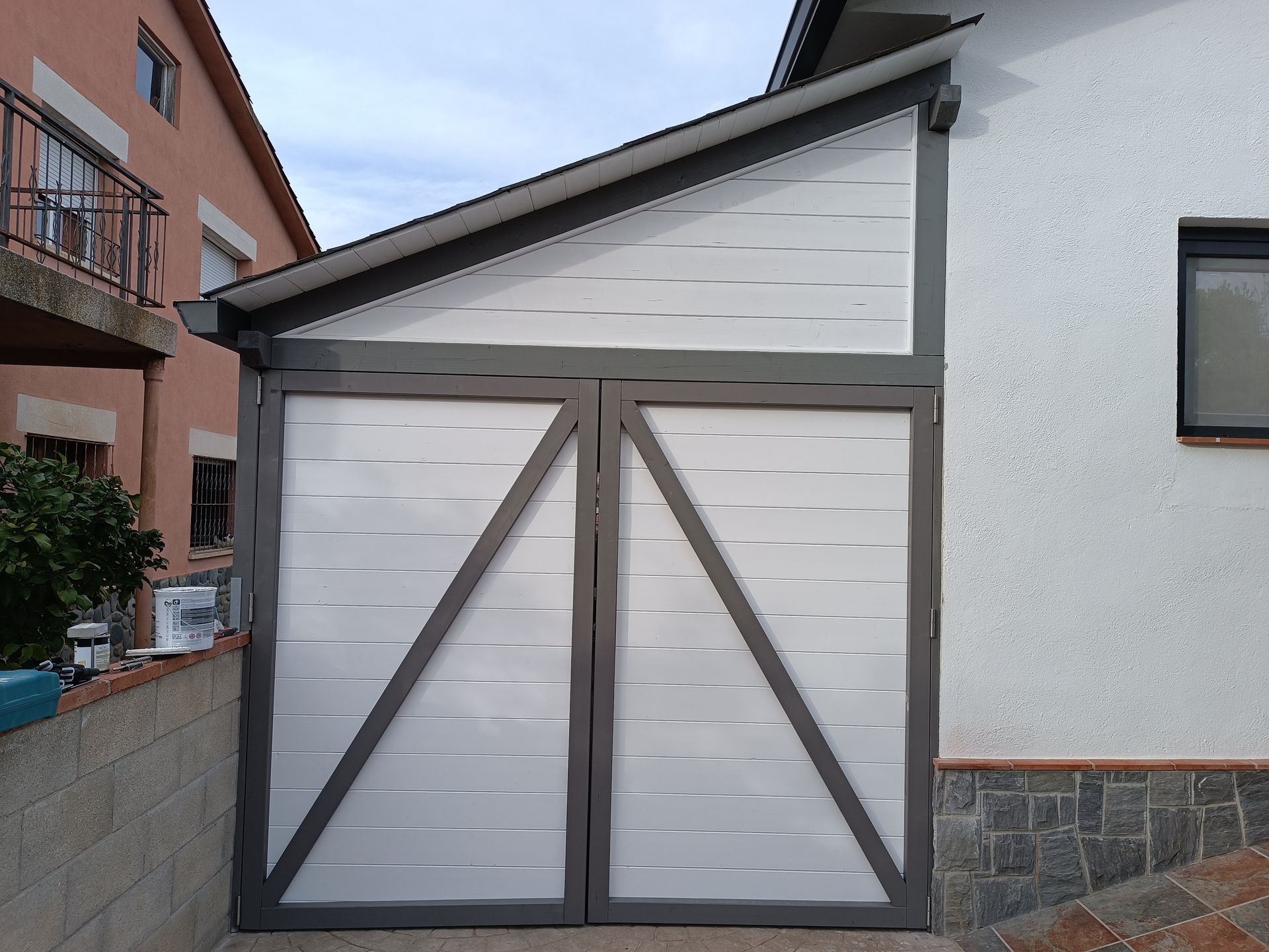 Una puerta de garaje blanca está sentada al costado de una casa.